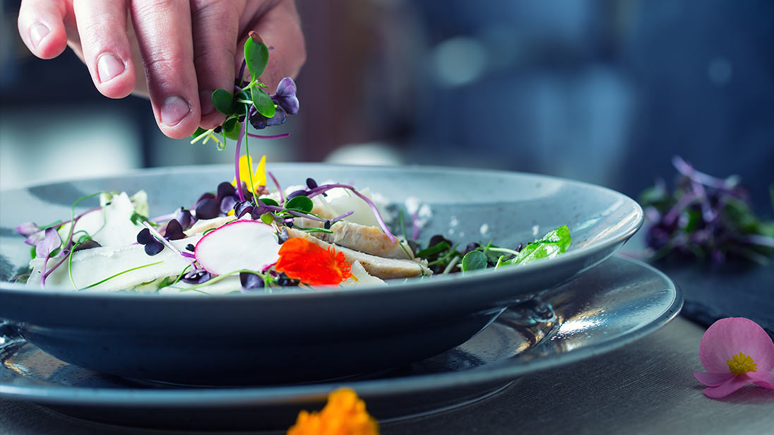 Image of a chef placing florals on a dish