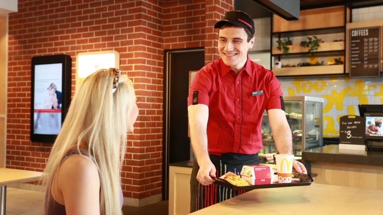 Photo shows a McDonald's worker serving food to a table