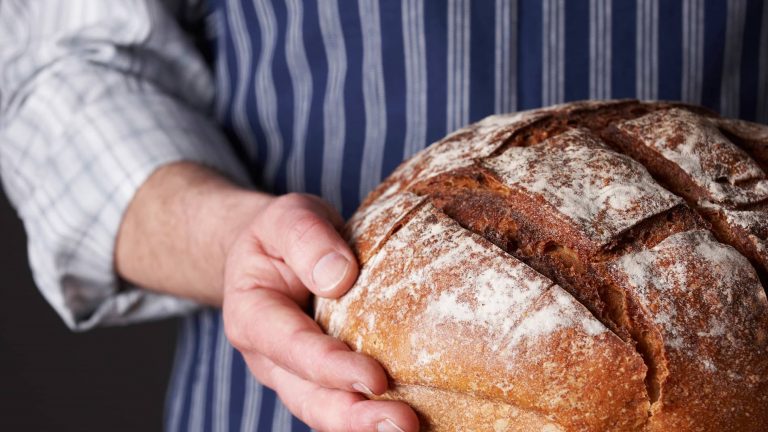 Baker holding a crusty bread loaf