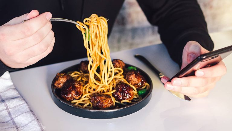 Image of someone eating on their own using their phone