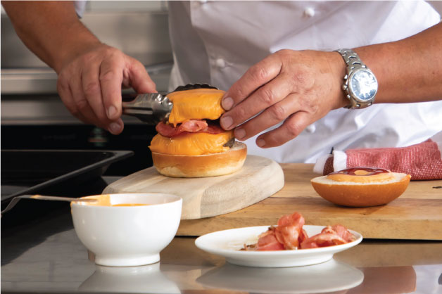Chef adding the bun on top of a burger